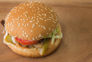 Selective focus of tomato in  hamburger on wood table in kitchen. Junk food concept.
