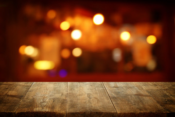 Image of wooden table in front of abstract blurred restaurant lights background