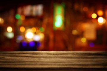 Image of wooden table in front of abstract blurred restaurant lights background
