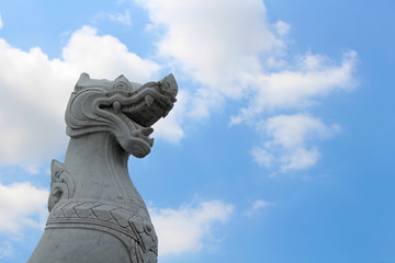 White Thai dragon statue under a blue sky.