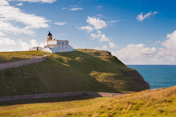 Fototapeta na wymiar Lighthouse on a rocky coast in highlands of Scotland