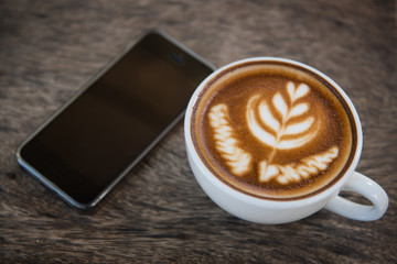  cup of coffee on wooden table. latte art coffee and phone.