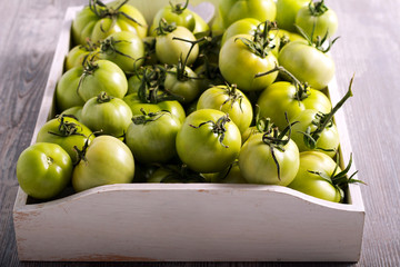 Raw green tomatoes in wooden box