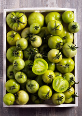 Raw green tomatoes in wooden box