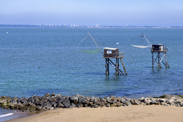Fototapeta na wymiar Fishing carrelets and the town of Saint Nazaire in the background, at Saint-Michel-Chef-Chef in the Loire-Atlantique department in western France.