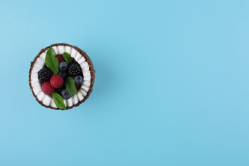 Coconut on blue background with berries.