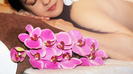 Obraz na płótnie Canvas Beautiful young woman in spa salon getting massage with spa stones, on dark background