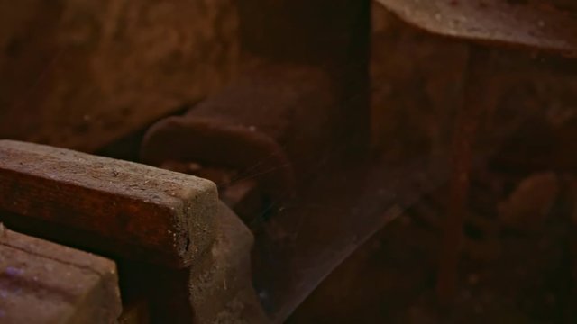 abandoned place smithy. Moving from a rusty vise over a hammer to a vise with spider web. The wall behind is made of natural stone. The workshop is very old and decays.