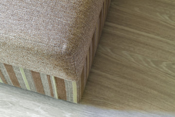 Detail of a modern beige textured sofa in living room on wooden laminate parquet floor.