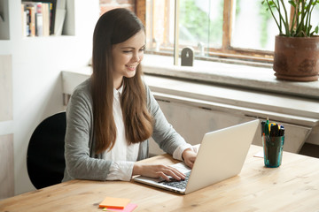 Happy smiling businesswoman working  on laptop. Young casual office worker composing positive...