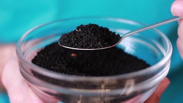Taking a spoon with black cumin seeds