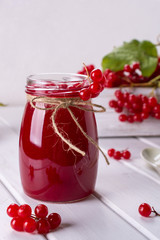 Glass jar of homemade viburnum jam with fresh berries  on white table.