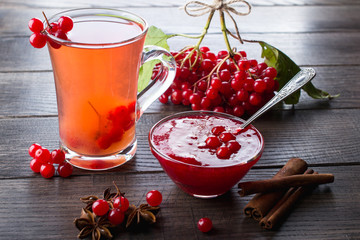 Hot spicy beverage with viburnum in glass cups  with fresh viburnum berries and cinnamon sticks, anise stars on a dark kitchen table.  