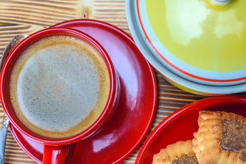 cookies on a red plate and coffee in a red mug standing on a wooden background 