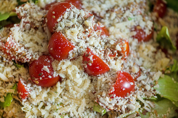 Macro shot of sunflower seeds, sesame, lin seeds on top of red cherry tomatoes next to parmesan cheese, lettuce, chicken. Freshly made caesar salads with dressing. Healthy vegetables, food in summer