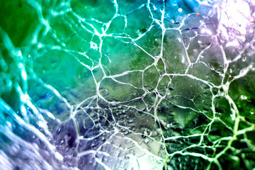 Macro shot of broken, cracked glass ball on colorful rainbow background. Glass reflecting light on sunny summer day. Future prediction, fortune telling in crystal ball. Abstract, esoteric background.