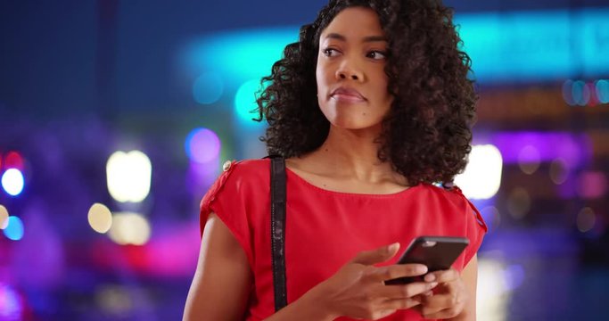 Pretty African female texting on cellphone, colorful fountain in background