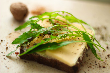 Sandwich from black bread with cheese and arugula
