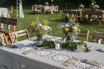 Stacked tables for guests for rustic outdoor wedding ceremony of green lawn in countryside house garden