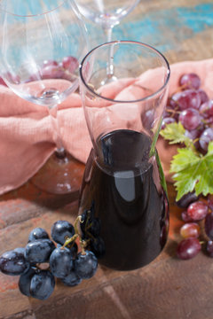 Small carafe with dry red wine, two wine glasses and grapes