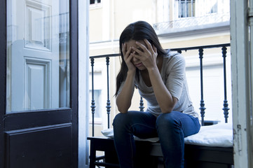 desperate Latin woman sitting at home balcony looking destroyed and depressed suffering depression