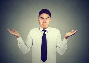 Closeup portrait young business man shrugging shoulders