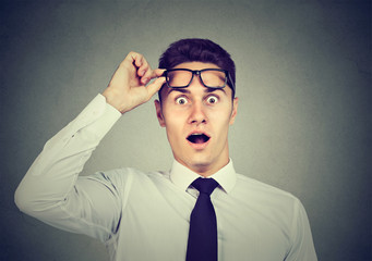 Wow! Surprised handsome man with opened mouth taking off glasses