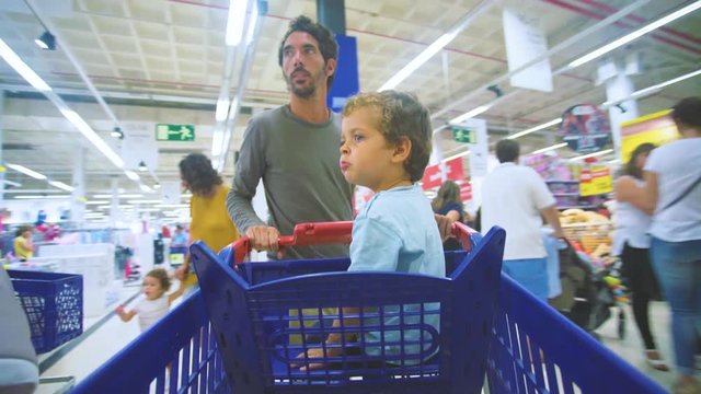 Father shopping in the supermarket with childs inside de chart shopping