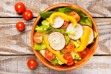 Fresh healthy close up salad with cos lettuce, cherry tomatoes, bell pepper, radish on  wooden background top view,food and health.