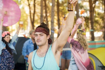 Young man holding beer bottle at campsite