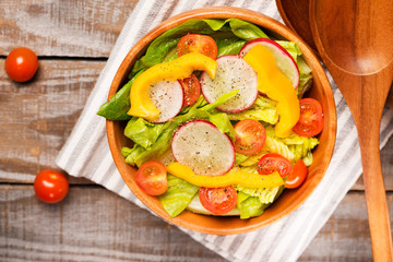 Fresh healthy  salad on wooden background top view with cotton napkin