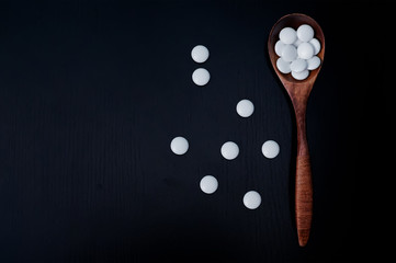 Vitamin capsules in a wooden spoon