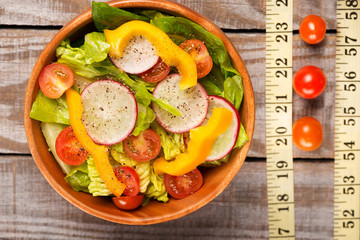 close up with salad on wooden table with measuring tape on wood background.