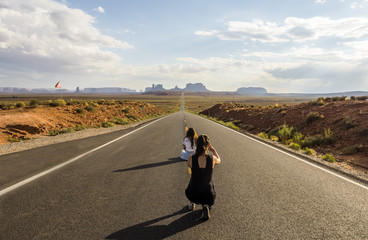 Forest Gump Point, tourist girls taking pictures - Monument Valley scenic panorama on the road - Arizona, AZ, USA