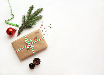 Obraz premium Christmas or New Year background with copy space. Christmas composition made of decorations: gift, red ball, fir branch, pine cones, fir branch and gift on textured white background. Flat lay.