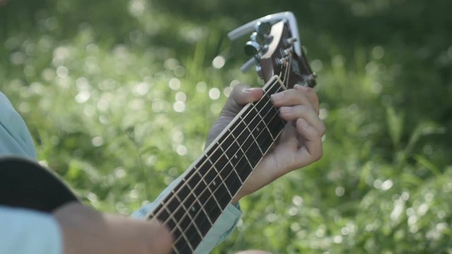The musician clamps the chords on the guitar close-up