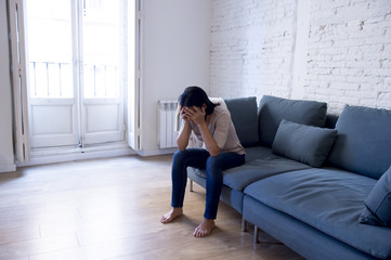 young attractive latin woman lying at home couch worried suffering depression feeling sad and...