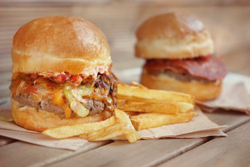 Tasty burgers with french fries on wooden table
