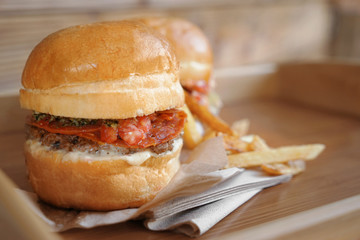 Tasty burgers with french fries on wooden tray