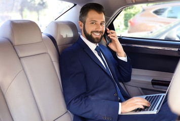 Businessman in elegant suit on backseat of car