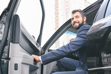 Handsome man in suit getting out of car - Powered by Adobe