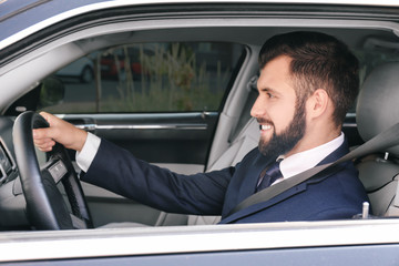 Fototapeta na wymiar Handsome man in formal suit on driver's seat of car