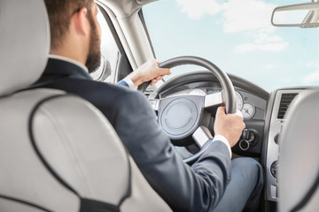Man in formal suit on driver's seat of car