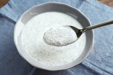 Spoon with delicious chia seed pudding over bowl on table