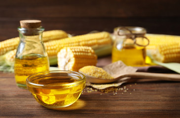 Glassware with corn oil on wooden background