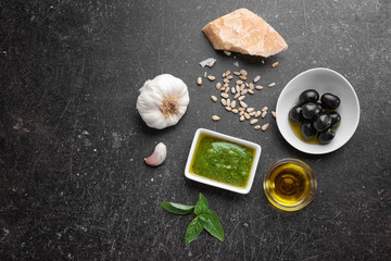 Composition with bowl of delicious basil pesto sauce on grey background