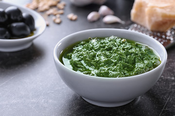 Bowl with delicious basil pesto sauce on table