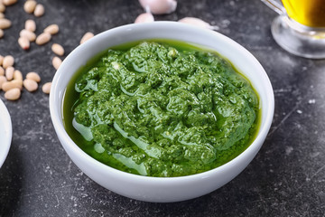 Bowl with delicious basil pesto sauce on table, close up