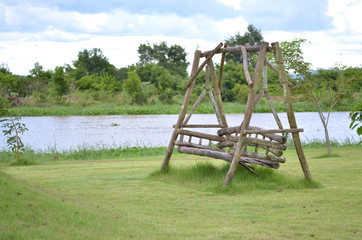 Fototapeta na wymiar Old swing wood chair on grass near river 
