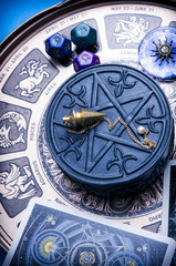 zodiac ring, pendulum, dice with astrology symbols lying on horoscope and magic pentagram 